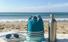 Notre sac en toile enduite trouve naturellement sa place sur la serviette et on y loge tous nos indispensables ! 