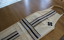 Tablier de cuisine plié avec poche centrale et broderie croix basque. 