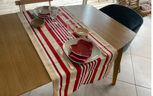 Chemin de table Gorri en coton satiné beige à rayures rouges sur une table dressée