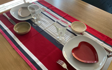 Détail du tissu satiné du chemin de table ARROZA rouge à rayures grises, noires et roses